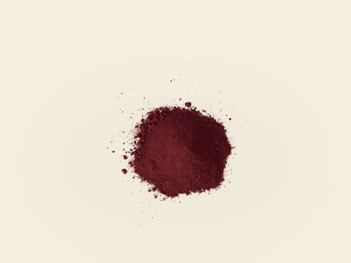 Crimson beetroot powder in a wooden bowl with splash